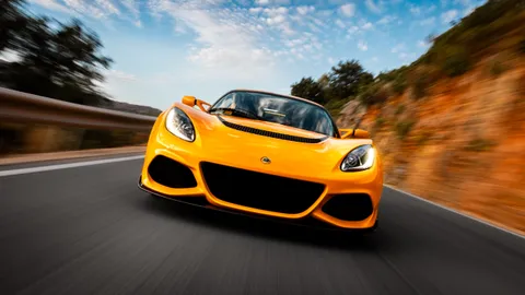 The Exige head-on through a fast corner, cliff face streaking past